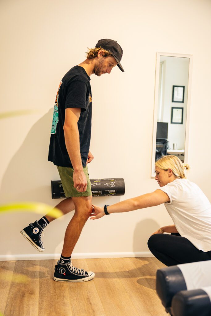 Female chiropractor treating male patients knee