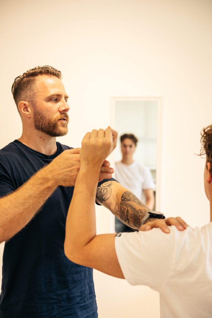 Male chiropractor assessing the the external rotation limitations on a male patient's shoulder.