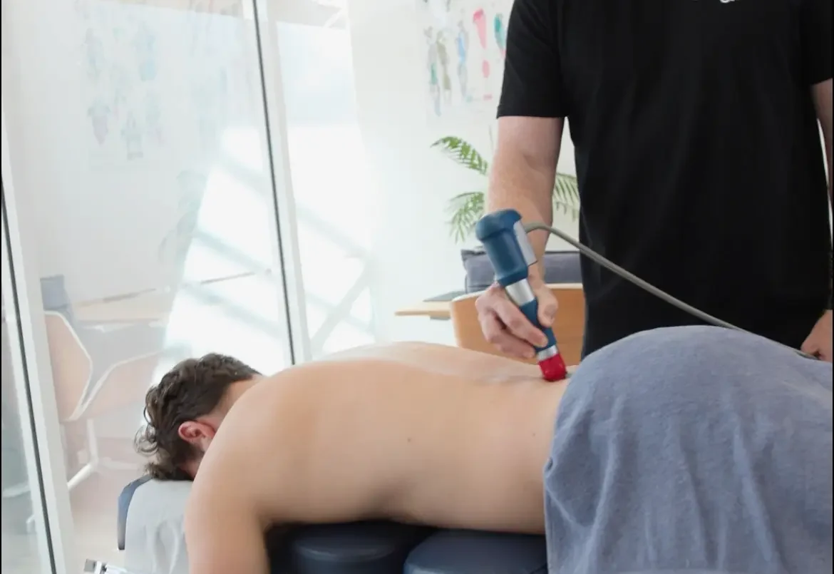 Male practitioner treating low back pain with shockwave