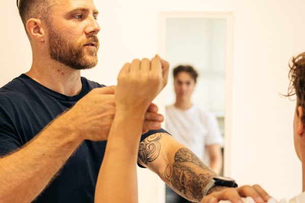 Male chiropractor assessing the the external rotation limitations on a male patient's shoulder.