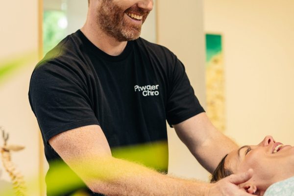 Male chiropractor mobilising female patients neck to relieve neck pain.